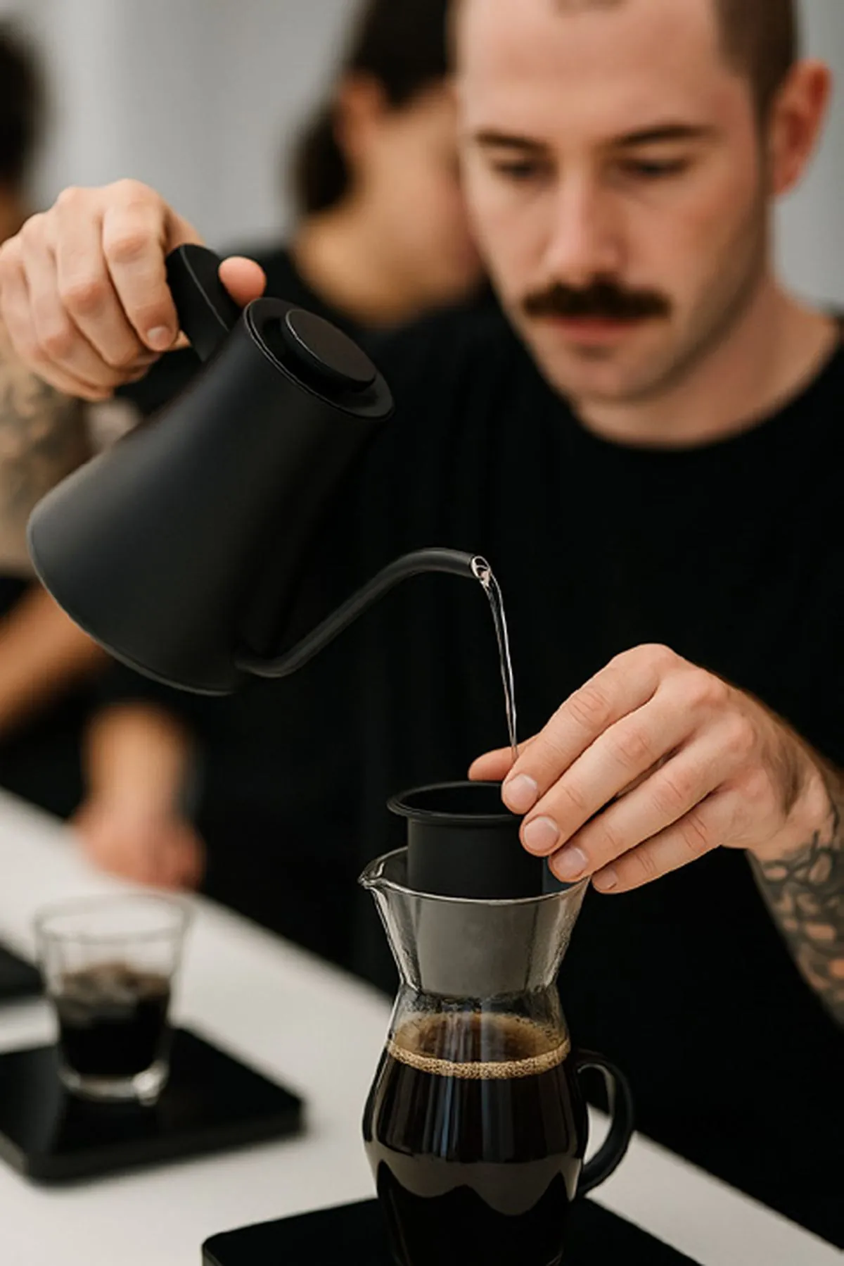 Barista pouring from a kettle over a filter at The Grounds